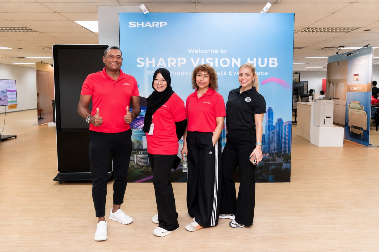 Four participants posing at a Sharp Vision Hub event backdrop