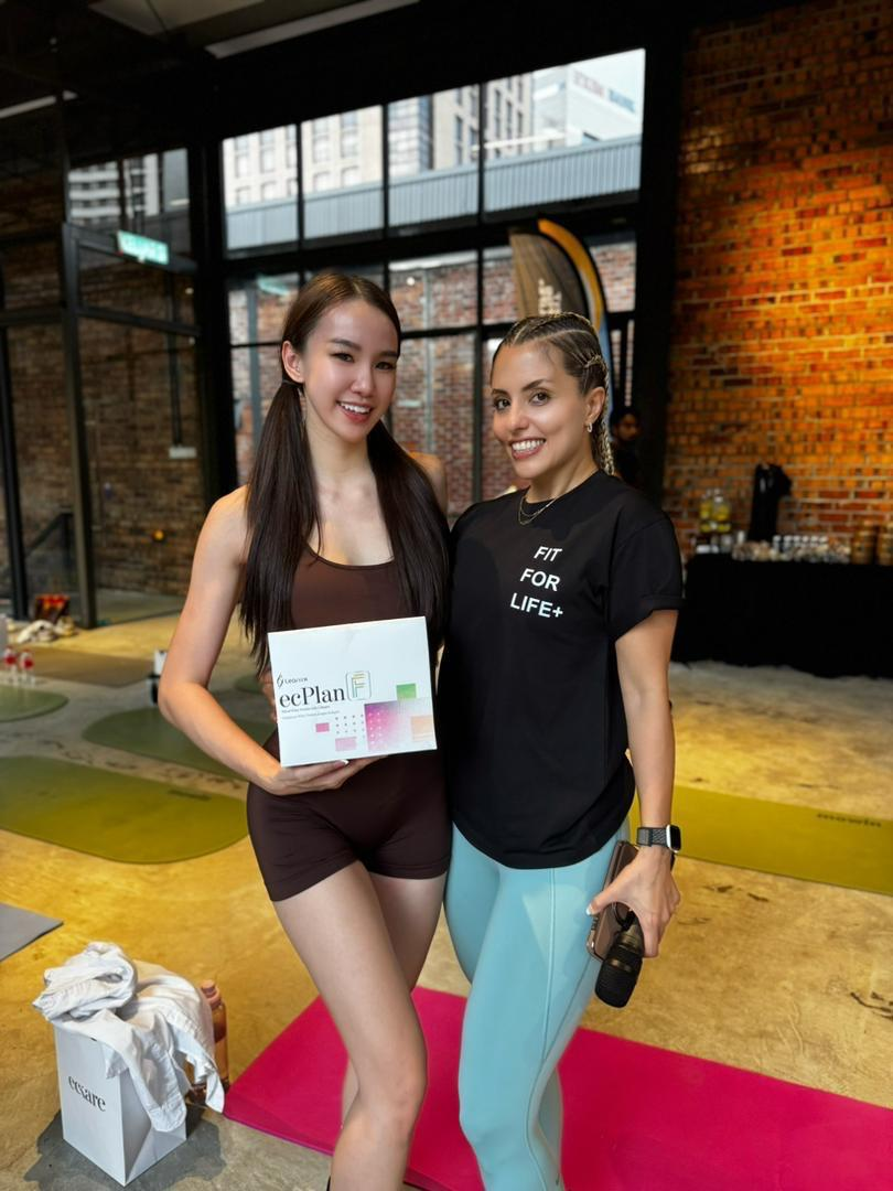 Two participants posing with a wellness product box at an event