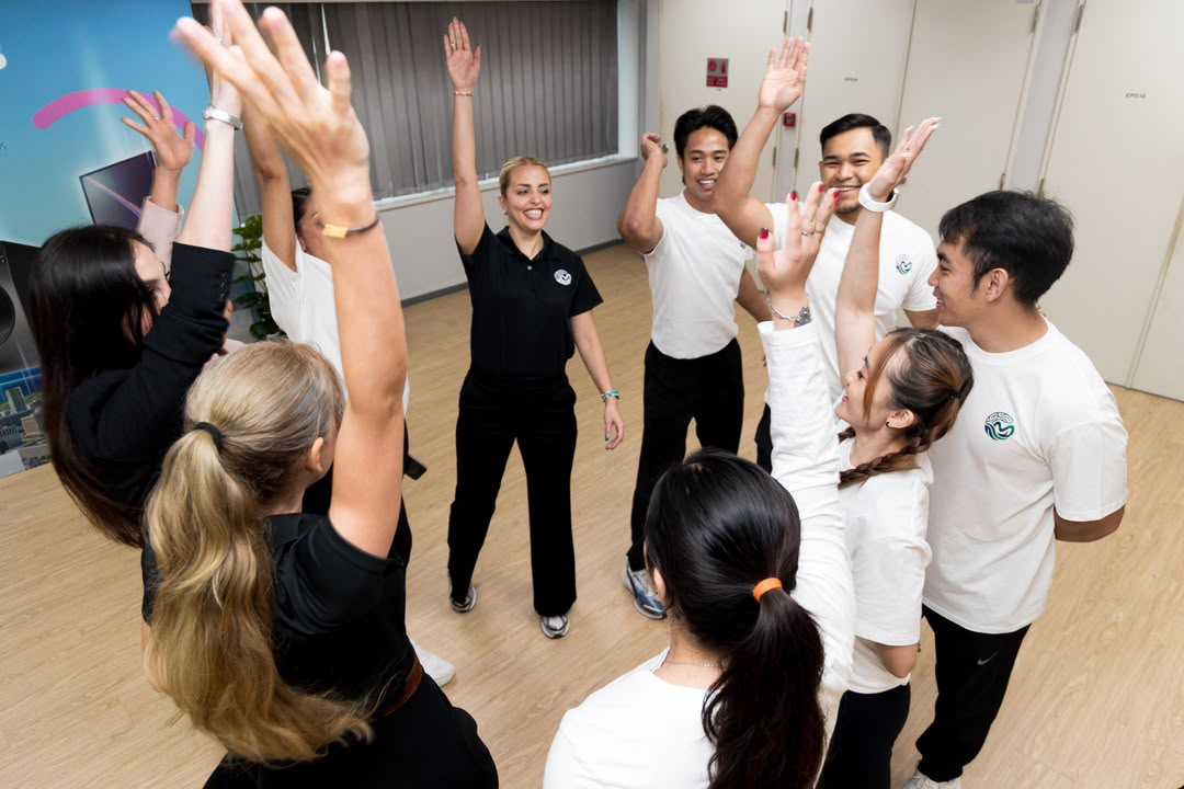 A large group performing a guided wellness pose on individual mats